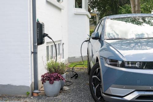 a car parked next to a house with a charging station at Sdr. Omme Bed & Breakfast in Sønder Omme