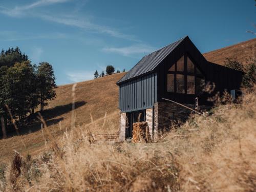 a small black building on a hill in a field at Horská chata Termoska in Rokytnice nad Jizerou