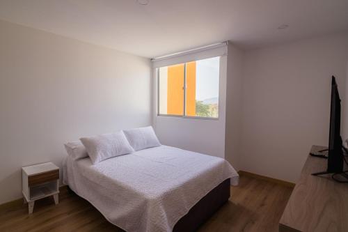 a white bedroom with a bed and a window at Penthouse en Pitalito in Pitalito