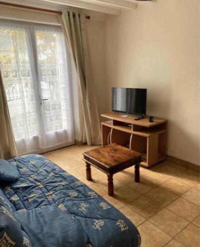 une chambre avec un lit et un bureau avec une télévision dans l'établissement Maison Vierville, à Vierville-sur-Mer