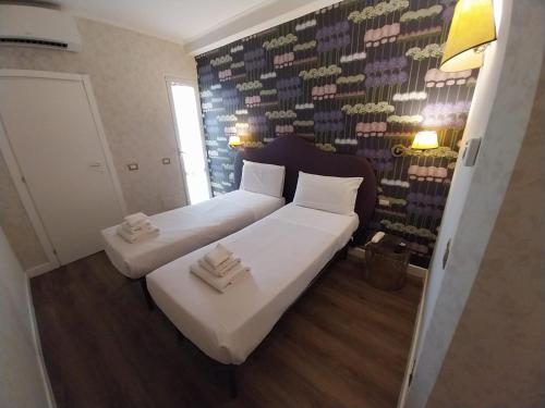 two beds in a room with a wall of wine bottles at Hotel Montreal in Florence