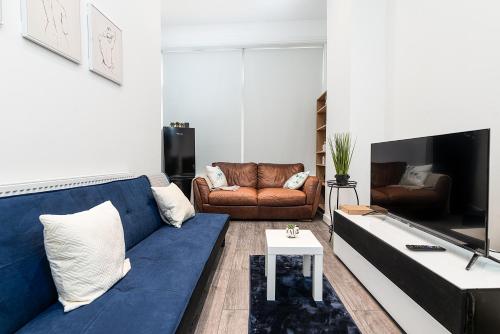 a living room with a blue couch and a tv at Deluxe 2 Bedroom Apartment In City Centre in Nottingham