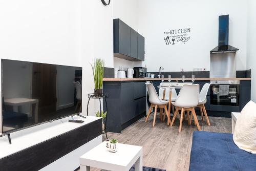 a living room with a large tv and a kitchen at Deluxe 2 Bedroom Apartment In City Centre in Nottingham