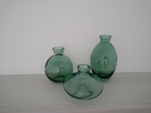 three green glass vases sitting on a table at Apartamento Sanin 3 in Lumbrales