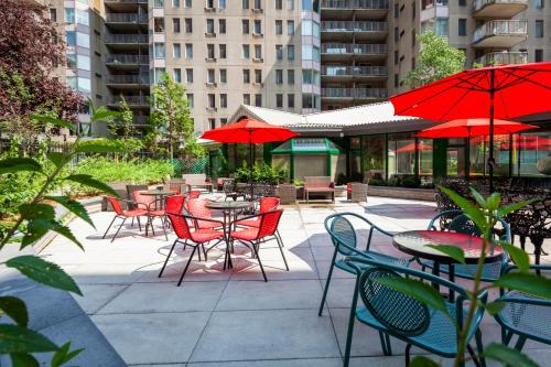 an outdoor patio with tables and chairs with red umbrellas at Le Nouvel Hotel in Montréal