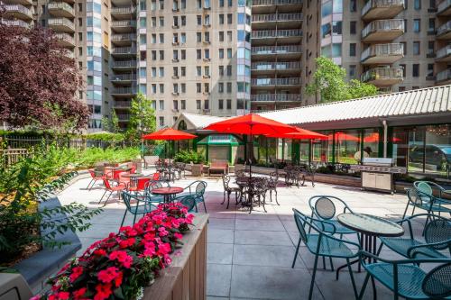 an outdoor patio with tables and chairs and red umbrellas at Le Nouvel Hotel in Montréal
