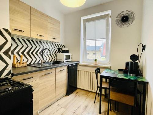 a kitchen with a counter and a table and a window at Blue Apartment close to Old Town in Bydgoszcz