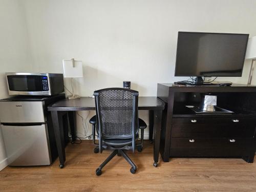 a desk with a computer and a microwave and a chair at H&H Motor Lodge in Idaho Springs