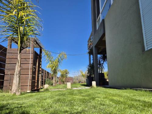 a building with a palm tree next to a yard at La Juanita Jose Ignacio in José Ignacio
