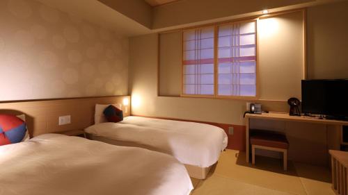 a hotel room with two beds and a television at Onyado Nono Kanazawa in Kanazawa