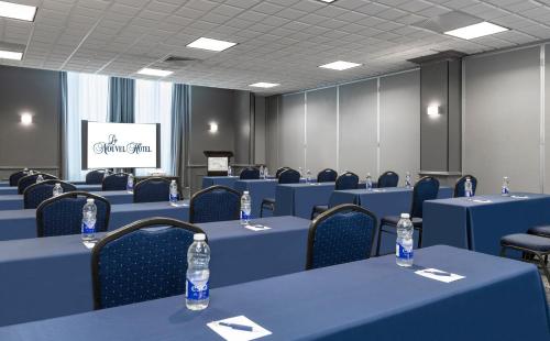 a conference room with blue tables and chairs and water bottles at Le Nouvel Hotel in Montréal