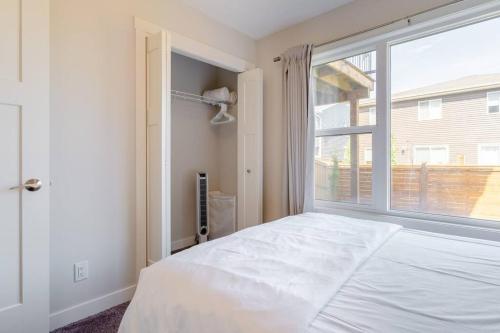 a bedroom with a white bed and a large window at Exquisite One Bedroom Apartment in NW in Calgary