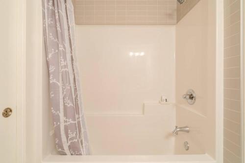 a bathroom with a tub and a shower curtain at Exquisite One Bedroom Apartment in NW in Calgary