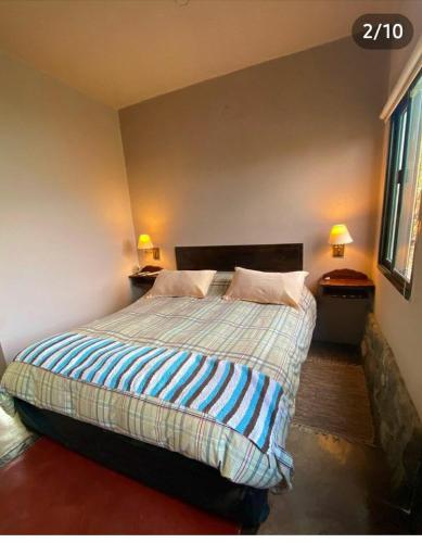 a bedroom with a bed with two lamps on the wall at Los Remolinos in Merlo