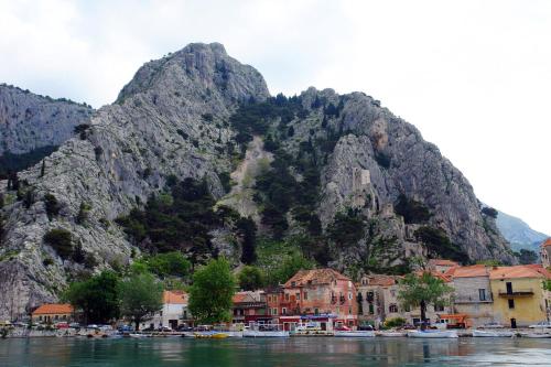a mountain next to a town with boats in the water at Tourist Settlement Brzet in Omiš
