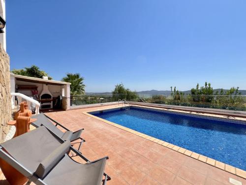a swimming pool with two chairs next to a house at Algarve Premium Villa With Pool by Homing in Santa Bárbara de Nexe