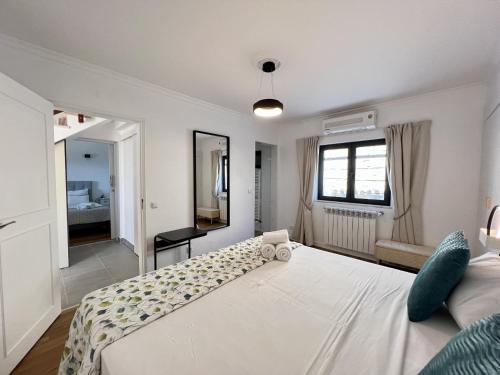 a bedroom with a large white bed and a mirror at Algarve Premium Villa With Pool by Homing in Santa Bárbara de Nexe