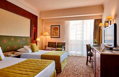 a hotel room with two beds and a television at Safir Hotel Cairo in Cairo
