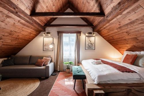 a attic bedroom with a bed and a couch at Chata Alpina Horní Mísečky in Horni Misecky