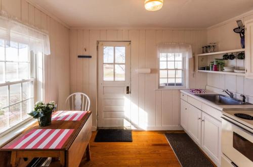 a kitchen with white cabinets and a table and a sink at Across from Mayo beach walk to downtown in Wellfleet