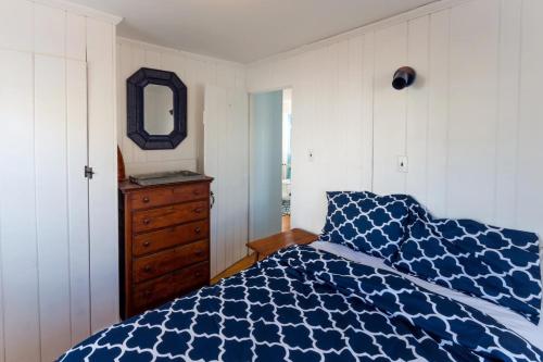 a bedroom with a blue and white bed and a dresser at Across from Mayo beach walk to downtown in Wellfleet