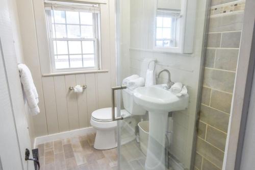 a white bathroom with a toilet and a sink at Across from Mayo beach walk to downtown in Wellfleet