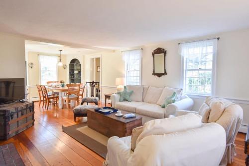 a living room with white furniture and a table at Heart of Brewster 5 Miles to Beach in Brewster