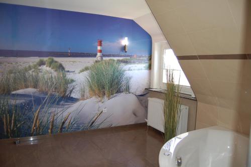 クックスハーフェンにあるStrandhaus Deichvoigtの照明の壁画とバスタブ付きのバスルーム