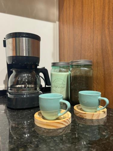 two cups and jars on a counter next to a coffee maker at Studio Avenida Paulista - Nex One Consolação in Sao Paulo