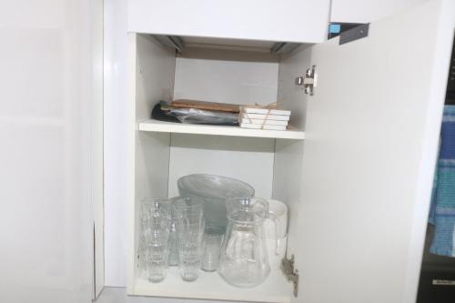 a cupboard filled with glass jars and other items at Le Moringa in Baie-Mahault