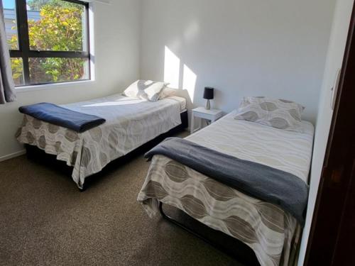 a bedroom with two beds and a window at Pohutukawa Cottage in Ohope Beach