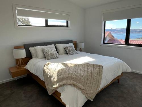 a white bedroom with a large bed with a window at Rusty's Ridge in Jindabyne