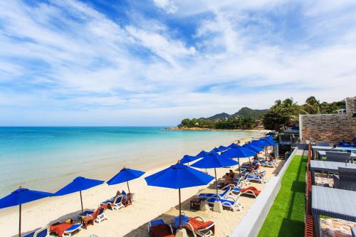 a beach with blue umbrellas and chairs and the ocean at Samui Resotel Beach Resort in Chaweng