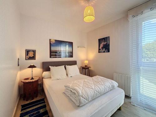 une chambre avec un lit, une lampe et une fenêtre dans l'établissement Appartement central avec balcon, parking privé - FR-1-361-66, à Granville