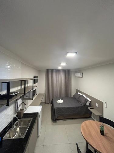 a bedroom with a bed and a table and a sink at Prédio San Paolo - Bairro Santa Mônica próximo a UFU / Prefeitura / Center Shopping in Uberlândia