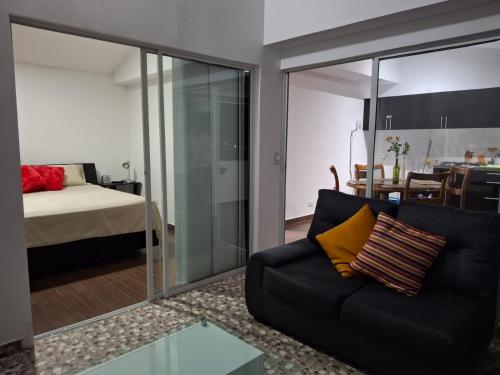 a living room with a black couch and a bedroom at Apartamento en un 4to piso cerca al coliseo en Armenia in Armenia
