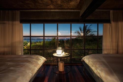a bedroom with two beds and a table in front of a window at Ocean View Riad Jeju in Jeju