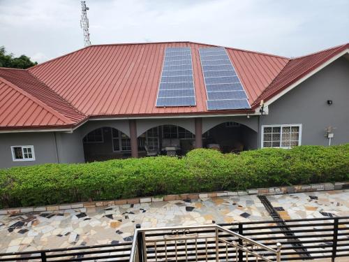 a house with a red roof with solar panels on it at Casa Consuelo Guest House in Takoradi