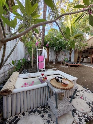 a bath tub in a backyard with a table and a chair at Gili Moonlight bungalows in Gili Air