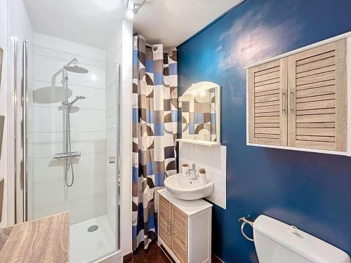 La salle de bains est pourvue de murs bleus, d'un lavabo et d'une douche. dans l'établissement Appartement RDC près de la plage avec terrasse et Wi-Fi - FR-1-361-555, à Jullouville