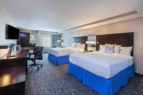 a hotel room with two beds and a desk at Courtyard Houston I-10 West/Park Row in Houston