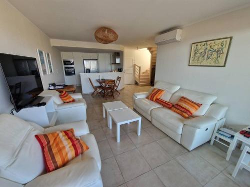 Il comprend un salon avec des canapés blancs et une cuisine. dans l'établissement Charmant appart climatisé 2 chambres avec terrasse et cuisine équipée - FR-1-100-344, à Cavalaire-sur-Mer