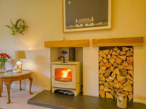 a wood burning stove in a room with a table at The Bellhouse - hot tub lodge in Tomatin in Tomatin