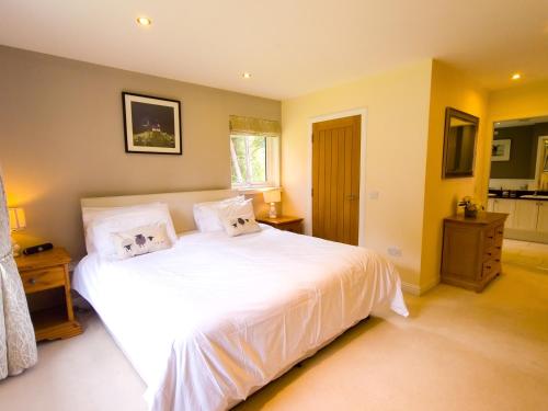 a bedroom with a large bed with white sheets at The Bellhouse - hot tub lodge in Tomatin in Tomatin