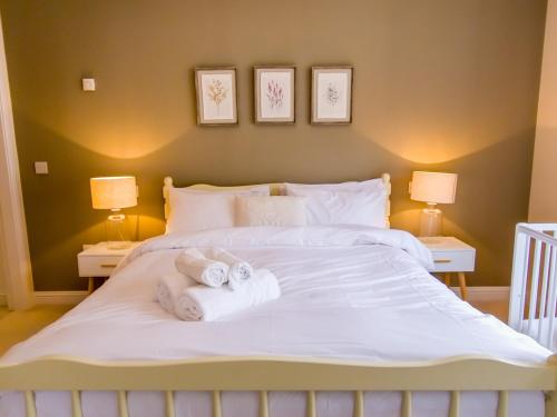 a bedroom with a large white bed with towels on it at The Bellhouse - hot tub lodge in Tomatin in Tomatin