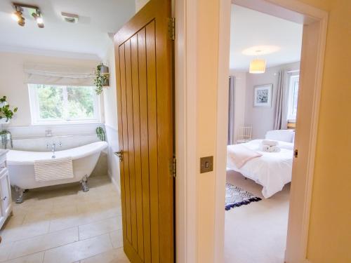 a bathroom with a tub and a bedroom with a bed at The Bellhouse - hot tub lodge in Tomatin in Tomatin