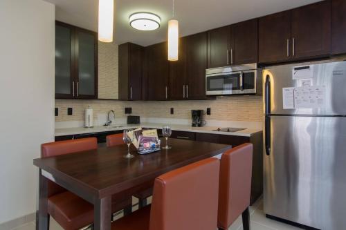a kitchen with a wooden table and a stainless steel refrigerator at Residence Inn Raleigh-Durham Airport/Brier Creek in Raleigh