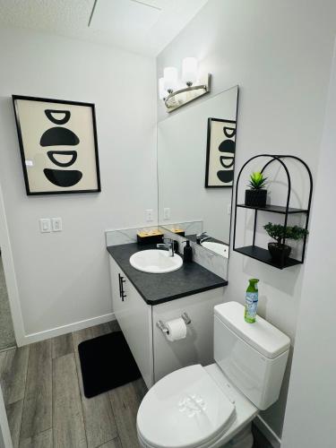 a bathroom with a white toilet and a sink at The Glacier Royale - 1 Bed Suite in NW Calgary in Calgary