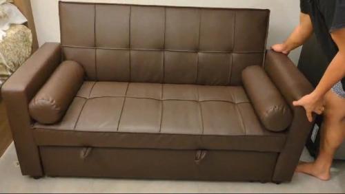 a woman standing next to a brown leather couch at 1809 Sunvida Tower Condo across SM City Cebu in Cebu City