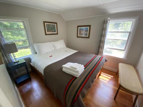 a bedroom with a bed and two windows at Bar Harbor Cottages & Suites in Bar Harbor